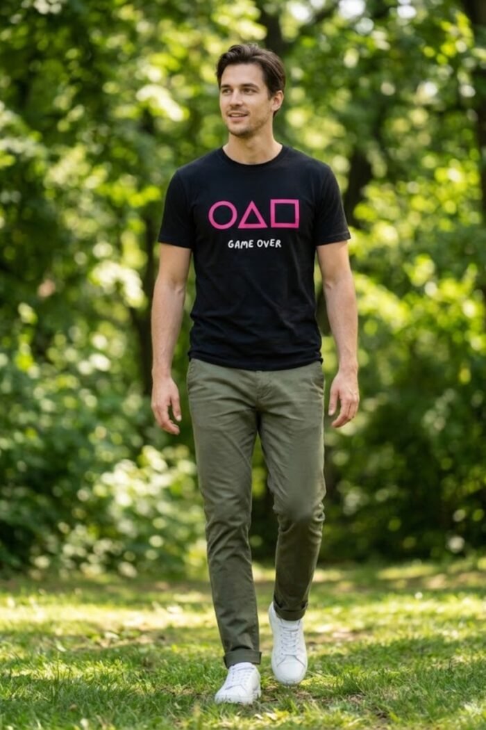 Man standing outdoors in a park wearing a black cotton t-shirt featuring the iconic Squid Game circle, triangle, and square symbols