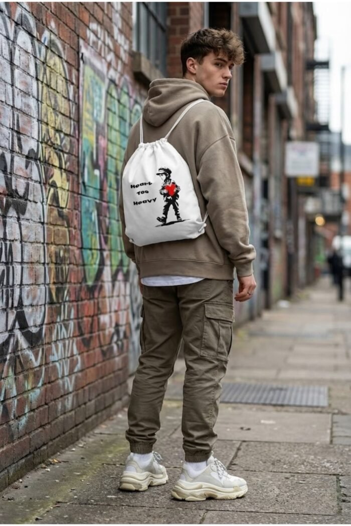 Model from behind wearing the Stilotee white canvas gym sackpack with abstract emotional lonely boy graphic print near a brick wall
