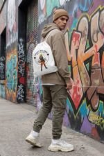 A product mockup collection showcasing the white aesthetic anime gym bag against an urban street art graffiti wall backdrop.