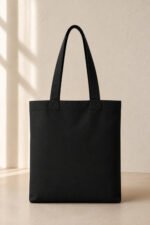 Back view of plain black heavyweight canvas tote bag showing clean finish, reinforced double shoulder straps, and durable structure