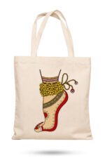 Off-white canvas tote bag featuring an Indian classical dancer foot adorned with golden ghungroo bells, red alta dye, and ornamental anklet with zipper closure.
