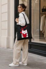 Model carrying cute chibi white kitten black canvas shoulder tote bag with graphic print