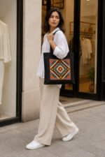 Lifestyle view of model in white outfit carrying midnight black bohemian geometric mandala canvas tote bag