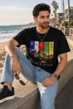 Man sitting outdoors wearing black Mountain Lover T-Shirt with colorful vertical mountain landscape print
